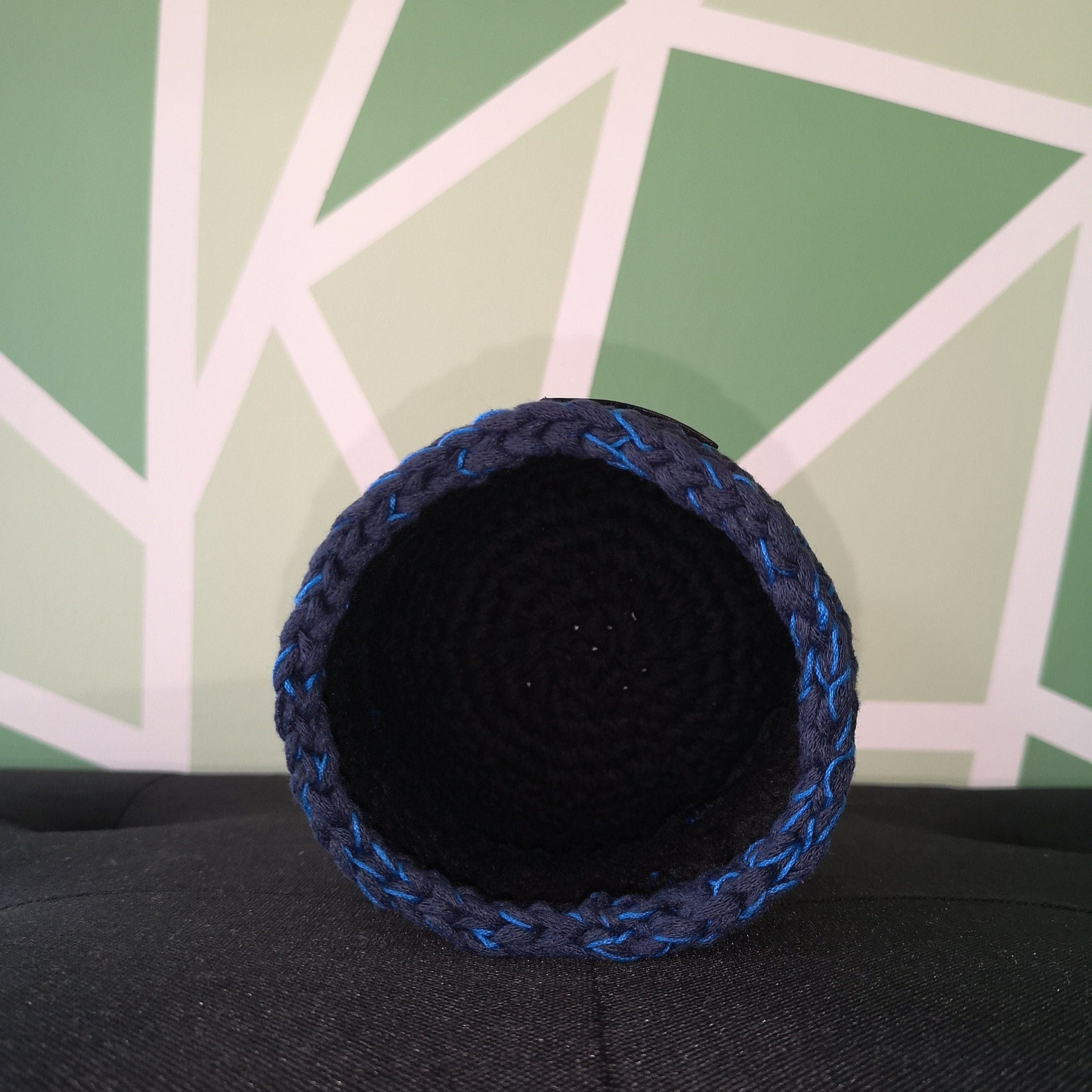 Petit pot au crochet noir et bleu posé sur la tranche