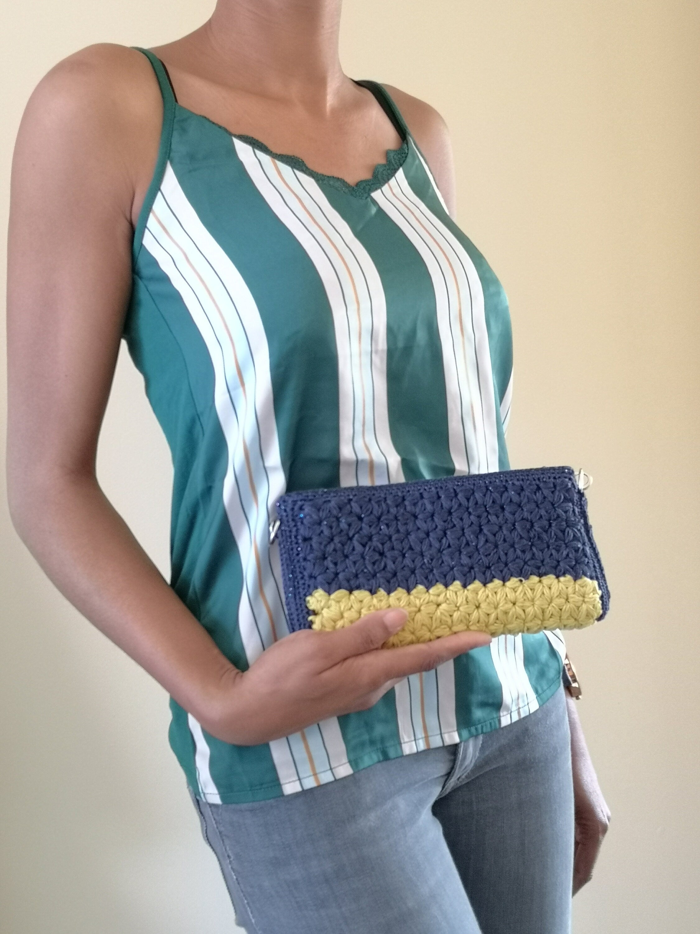 Pochette rigide au crochet jaune et bleu fil scintillant tenu a la main