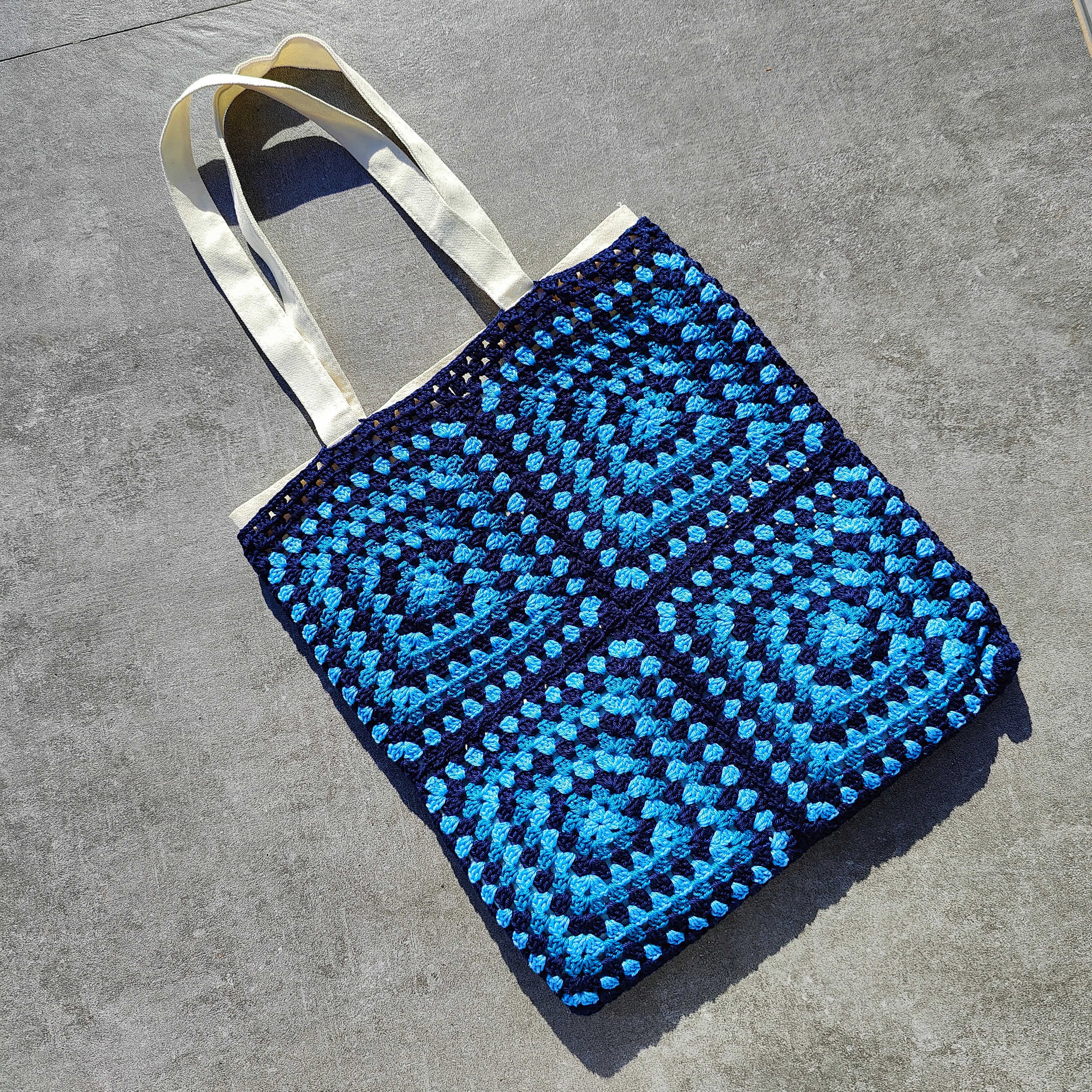 Tote bag fait main en granny square bleu et noir, avec anses crème, crocheté en fil Grundl.