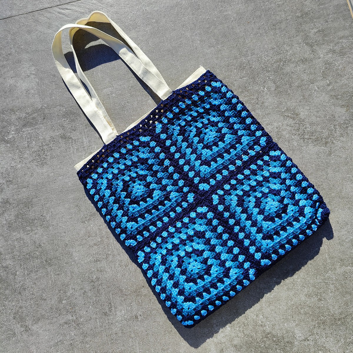 Tote bag fait main en granny square bleu et noir, avec anses crème, crocheté en fil Grundl.