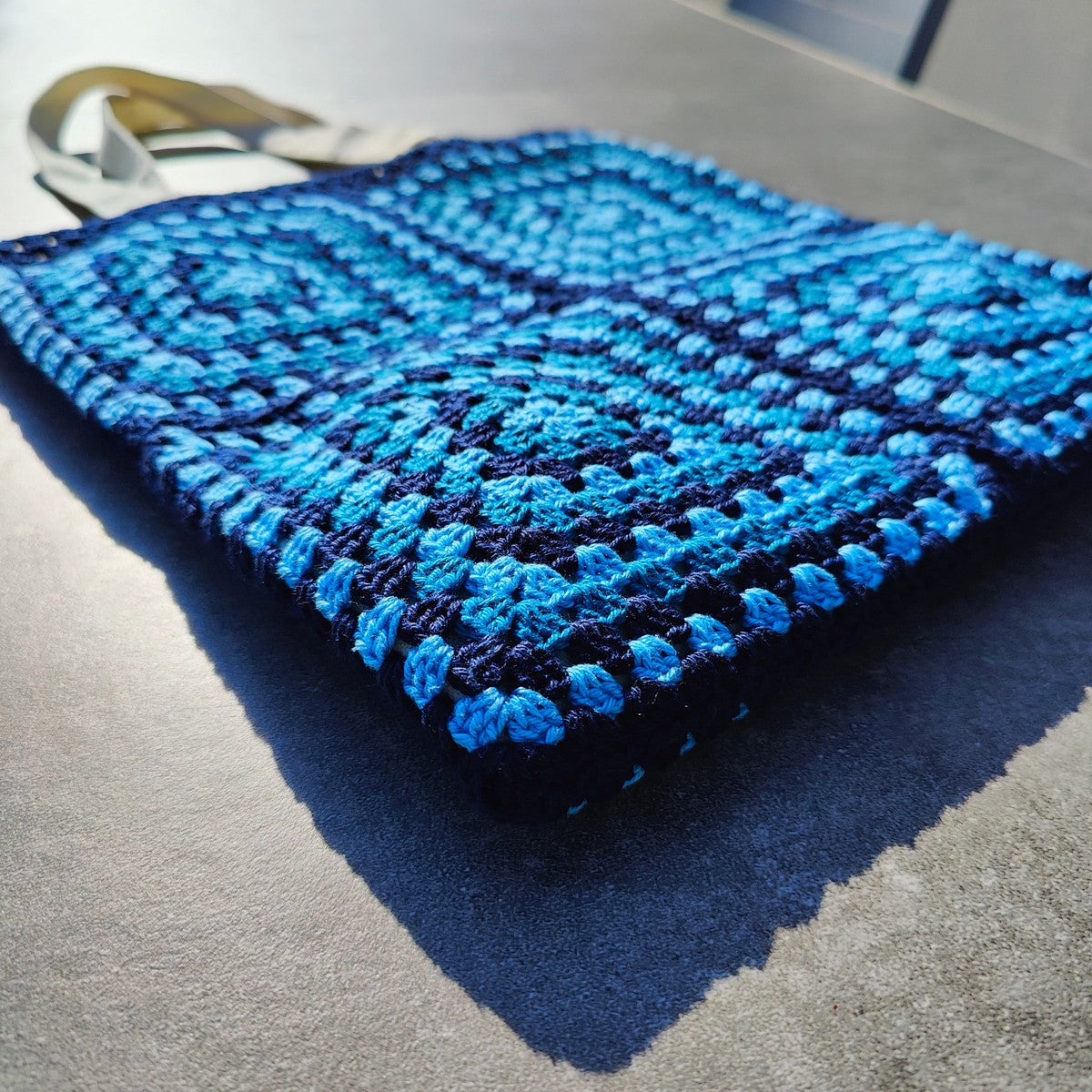 Tote bag fait main en granny square bleu et noir, avec anses crème, crocheté en fil Grundl.