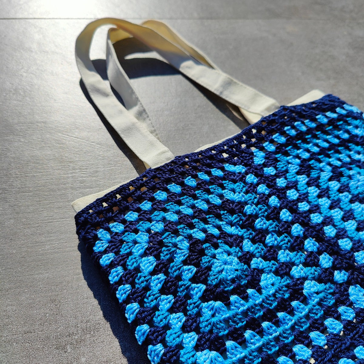 Tote bag fait main en granny square bleu et noir, avec anses crème, crocheté en fil Grundl.