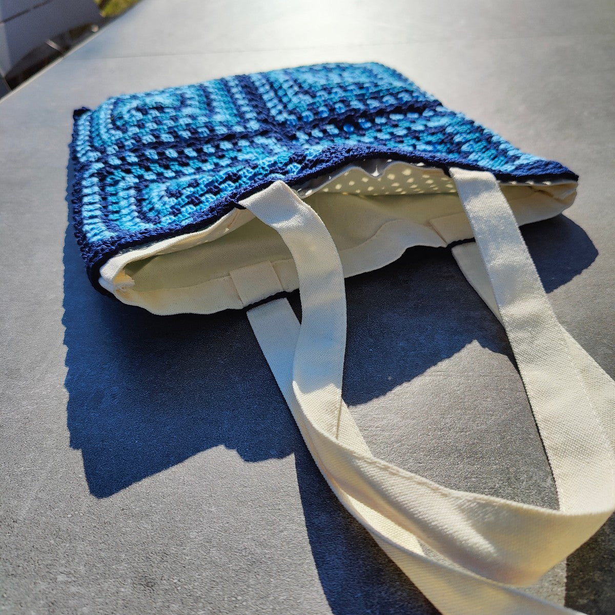 Tote bag fait main en granny square bleu et noir, avec anses crème, crocheté en fil Grundl.