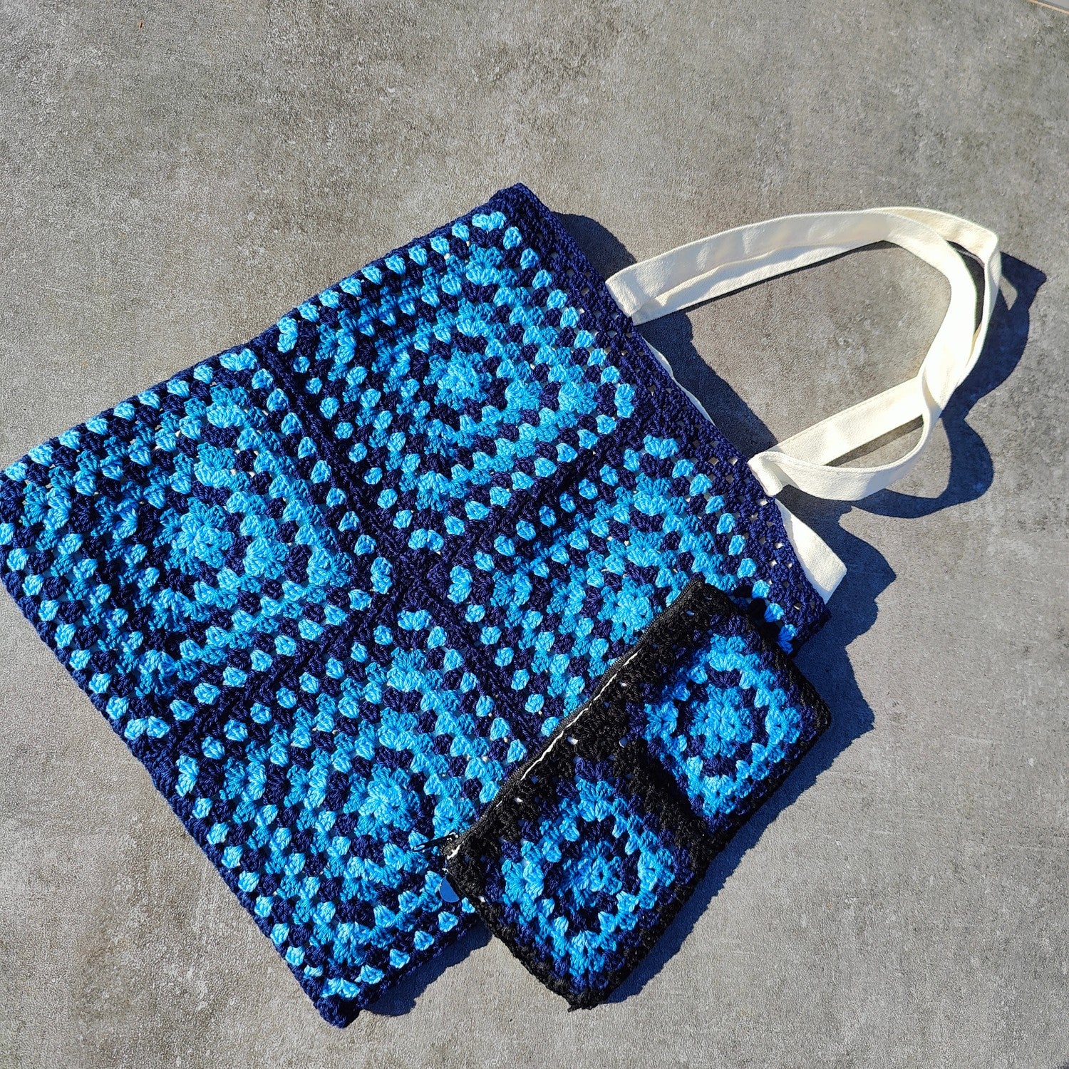 Tote bag fait main en granny square bleu et noir, avec anses crème, crocheté en fil Grundl.