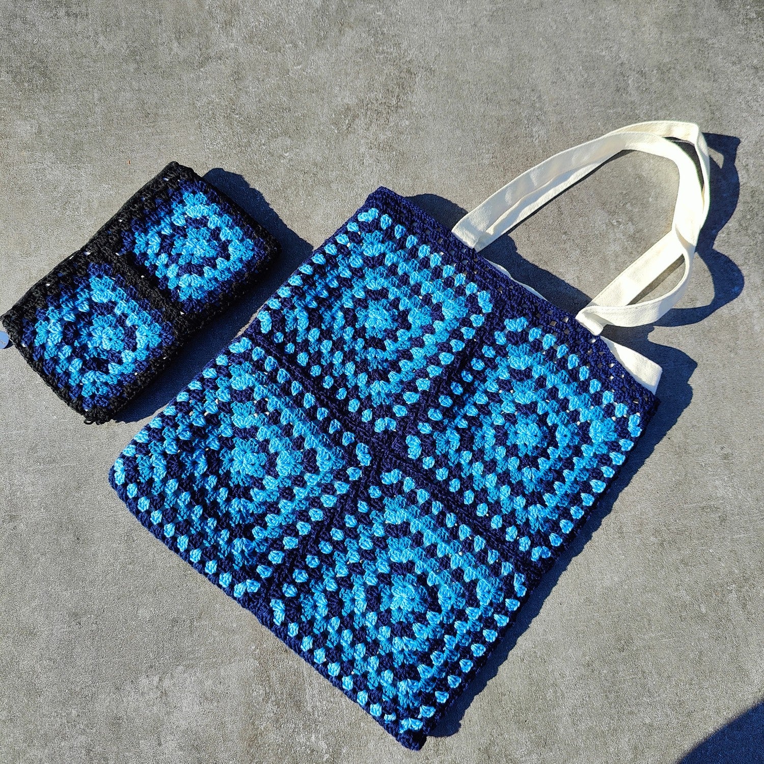 Tote bag fait main en granny square bleu et noir, avec anses crème, crocheté en fil Grundl.